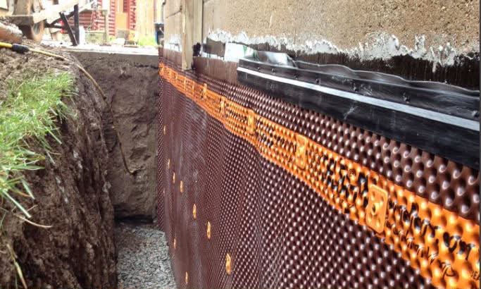 Dimple drainage board installed over waterproofed poured concrete foundation wall for water management